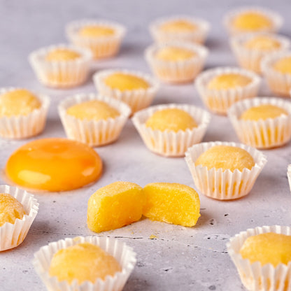 Yemas clásicas Santa Teresa en cápsulas de papel, con una yema partida que muestra su interior
